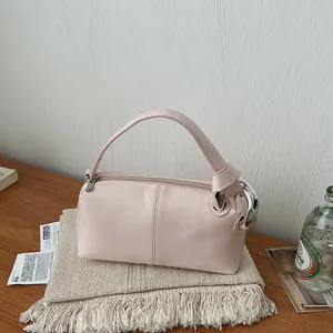 Close-up of a pale pink retro pillow handbag styled on a wooden desk with a textured background