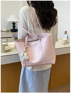 Detailed view of the stylish pink shoulder tote bag with cute bunny charm in cozy scene.