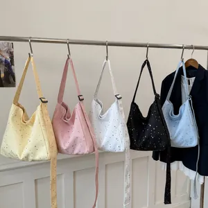 Five colors of canvas tote bags with sequin star patterns hanging on a metal rack.