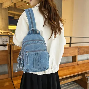 Stylish light blue denim backpack with multiple zipper pockets shown being worn by a model