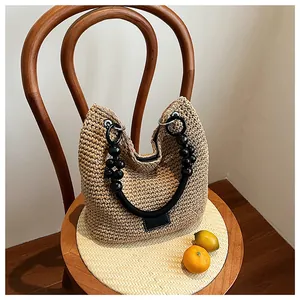 Stylish woven straw bucket bag with decorative black beaded handles shown in detail view.