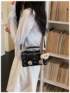Close-up detail of a vintage black polka dot crossbody bag featuring a cute bear plush charm