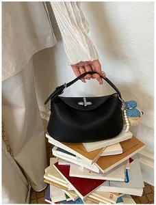 Detailed view of black textured leather bucket handbag with a decorative charm