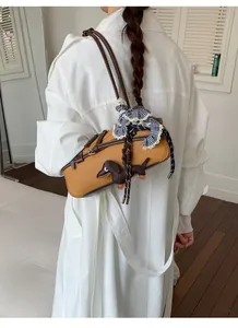 Yellow Boston shoulder bag with cute dog charm worn by a model in a stylish white coat