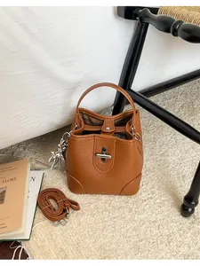 Détail d'un sac seau vintage marron avec fermoir tournant argenté et breloque chien