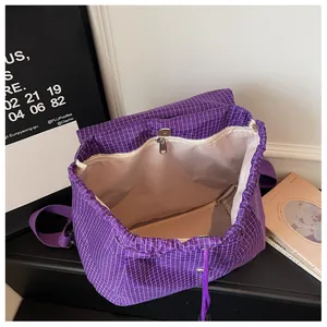 Detailed interior view of a purple grid casual backpack with a white lining and zipper pocket