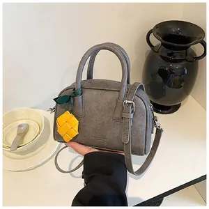 Sophisticated grey leather-textured pillow bag with a vibrant yellow pineapple charm.