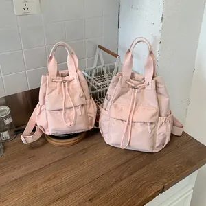 Primer plano de dos mochilas rosa claro con cordón en diferentes tamaños sobre madera