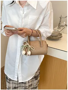 Detail of an elegant beige pillow bag featuring a decorative pearl tulip charm