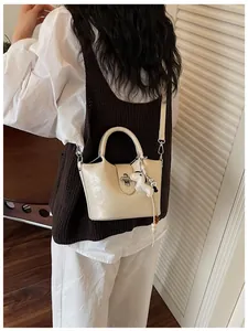 Vue arrière d'un sac seau chic en cuir crème avec un joli charme porté par un mannequin