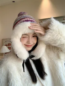 Close-up of a stylish winter trapper hat with thick white faux fur trim and colorful knit.