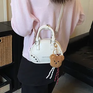 Close-up of a stylish white bowling handbag featuring a cute brown plush bear charm