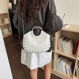 Detailed view of a white studded handbag with a round metal handle and silver chain strap