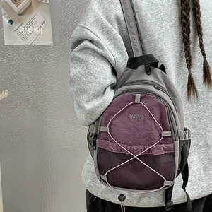 Vista detallada de una mini mochila gris y morada con cordones elásticos y bolsillos