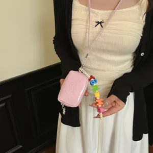 Close-up detail of a pink mini crossbody pouch with vibrant colorful letter beads.