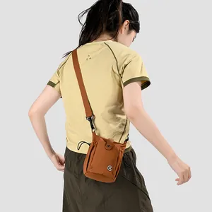 Jeune femme portant un mini sac à bandoulière marron pour téléphone avec sangle réglable.
