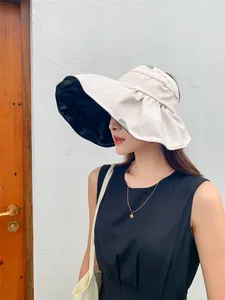 Detailed side view of a women's beige large-brimmed sun hat with black UV protection lining.