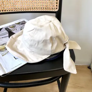 Vista detallada de un elegante sombrero de pescador de algodón blanco con un gran lazo.