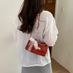 Elegant red quilted crossbody bag featuring a delicate white lace and pearl bow accent.