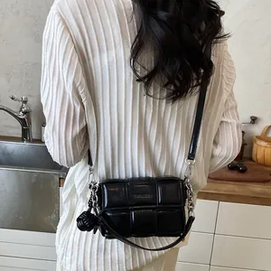 Stylish black woven texture small square shoulder bag worn by a woman in a kitchen.