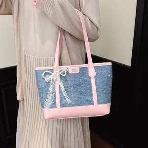 Détail du sac cabas en denim rose et bleu avec un nœud en dentelle et perles