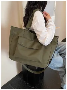 Detail view of a large olive green travel tote bag being carried by a model side on.