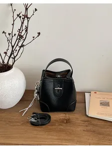Vue détaillée d'un sac seau en cuir grainé noir avec poignée et fermoir métallique