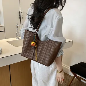 Bolso tote de cuero tejido marrón oscuro con colgante de tulipán llevado por modelo