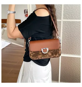 Elegante braune Umhängetasche aus Kunstleder mit Marmormuster und Silberschnalle an einem Model.