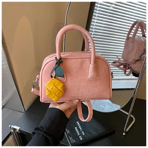Detailed view of pink suede pillow handbag with yellow pineapple charm accent