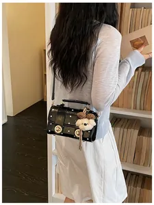 Retro black polka-dot crossbody bag with bear charm shown in lifestyle setting
