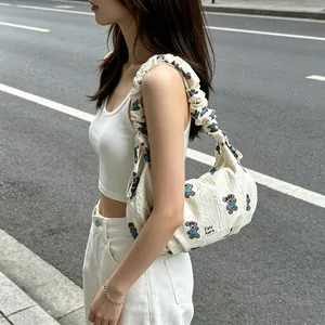 Fashionable white textured shoulder bag featuring cute blue t-shirt bear patterns shown on model