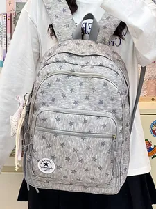 Large grey school backpack with star pattern and cute plush keychain being worn by a girl