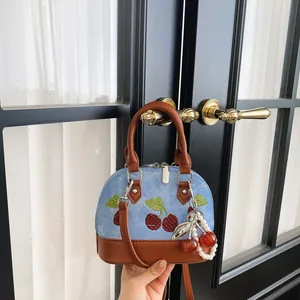 Bolso de mano vaquero con bordado de cerezas y colgante de perlas en un pomo de puerta