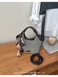 Vue détaillée d'un sac à main en paille tressée de style vintage avec breloque perlée sur table