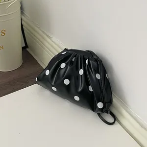 Detailed side view of a stylish black faux-leather dumpling bag with white polka dots