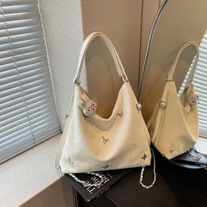 Detail of large capacity hobo bag with butterfly accents and rabbit charm by a mirror