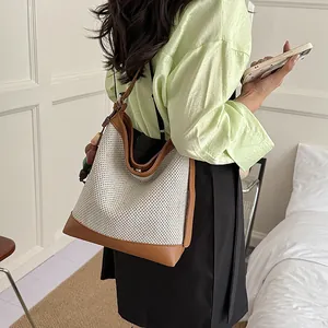 Stylish large capacity women's woven bucket bag with brown leather trim shown on model