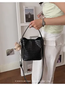 Detailed shot of a black woven bucket bag with bear charm in a vintage lifestyle setting
