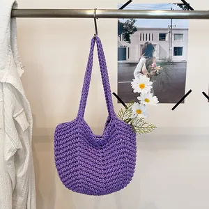 Handmade purple crochet hobo shoulder bag hanging on a hook with daisy and artistic background