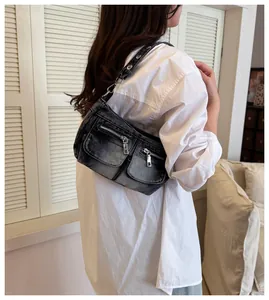 Stylish vintage washed denim shoulder bag with silver zipper pockets shown on model