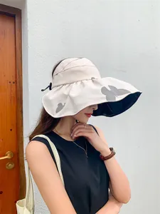 Side view of woman wearing a wide-brimmed butterfly print sun hat with black lining.