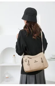 Detail view of a beige multi-layer crossbody bag worn by a model in a minimal setting.