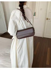 Minimalist brown baguette shoulder bag styled with a white dress for a casual look