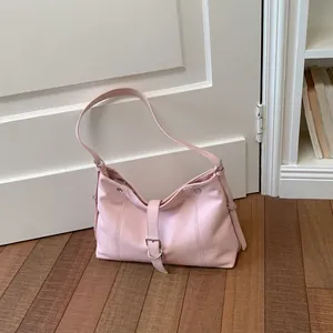 Stylish minimalist pink underarm tote bag featuring a silver buckle detail on wooden floor