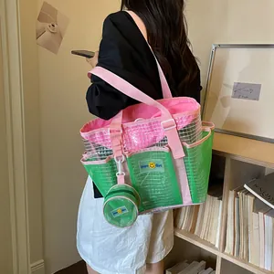 Detail shot of a large green and pink mesh tote bag being carried on the shoulder by a model