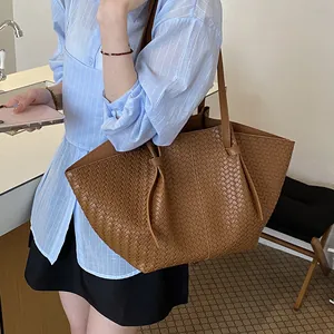 Close-up of brown woven leather tote bag with elegant texture and shoulder straps