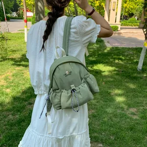 Vista trasera de una mini mochila verde salvia en un entorno de parque natural.