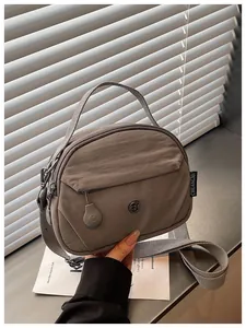 Primer plano detallado de un elegante bolso bandolera de nailon gris en la mano