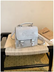 Close-up of silver academy style backpack with heart embroidery on a woven chair.